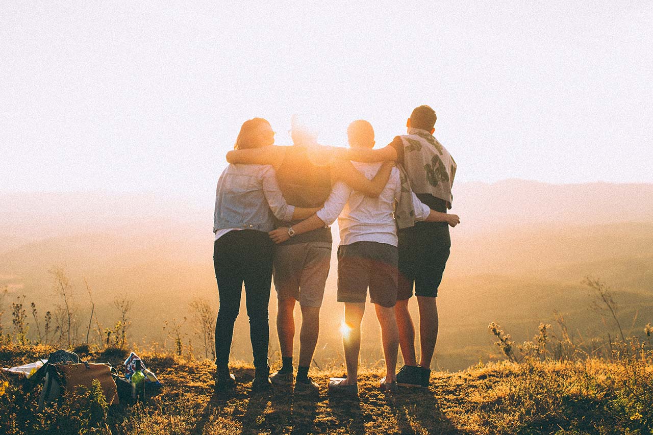 A group of four people on a hike look out towards the sunset