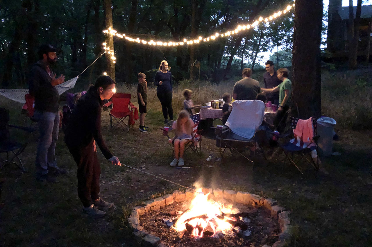 A group of children and adults gather around a campfire
